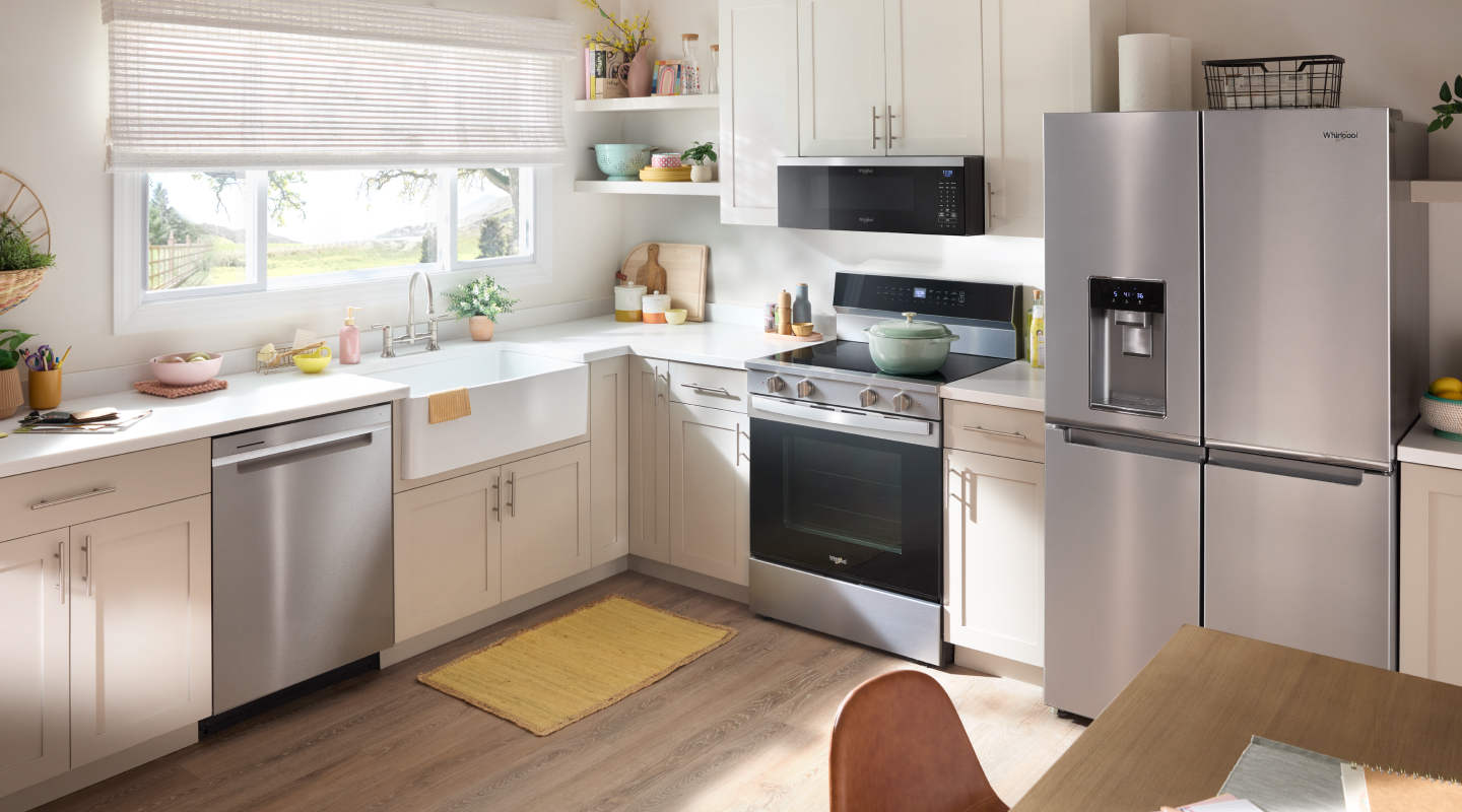 Stainless steel dishwasher, refrigerator and wall oven in kitchen with tan cabinetry.