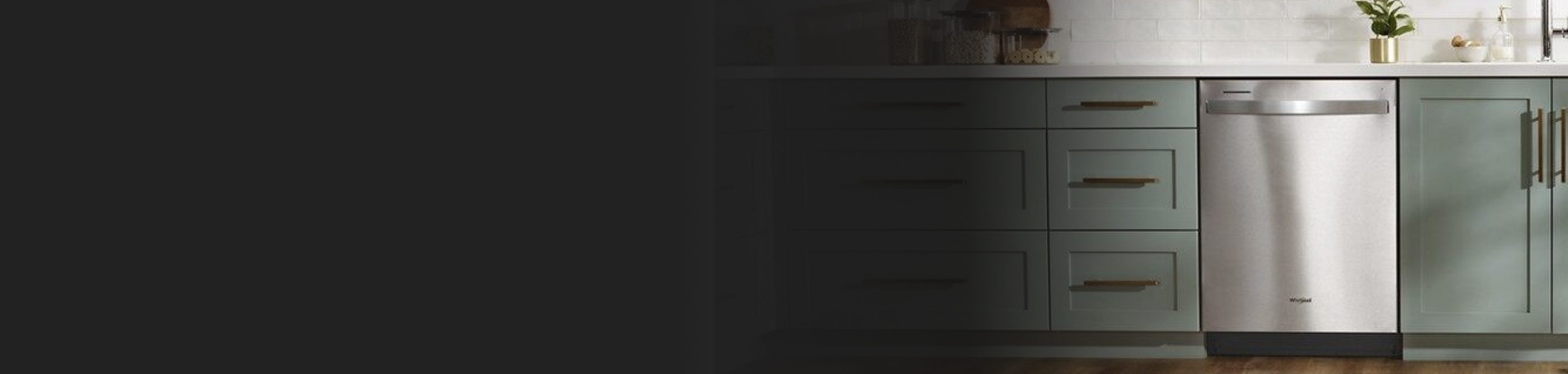 Stainless steel dishwasher in gray-green cabinetry. 