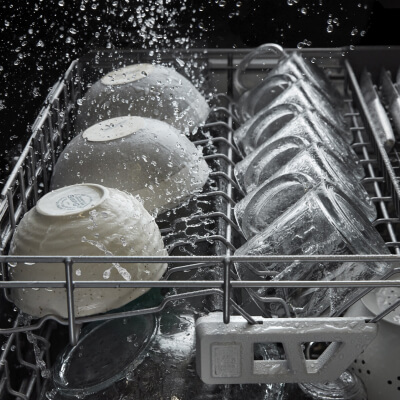 Bowls and mugs inside a dishwasher during a cycle