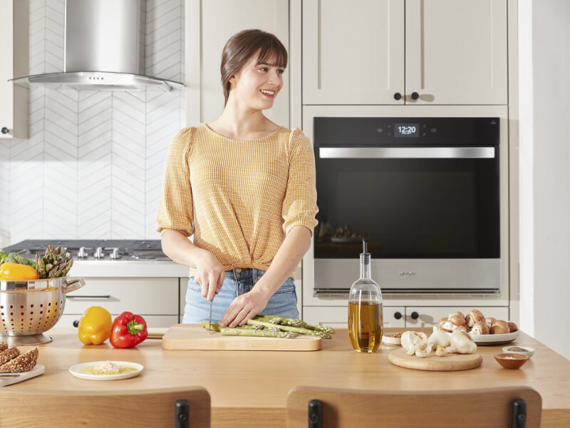Person standing at a kitchen island chopping vegetables on a cutting board