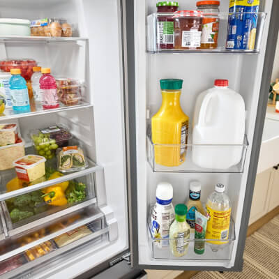 Open French door refrigerator with fully stocked door bins