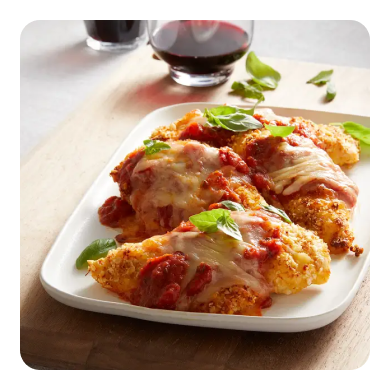 Breaded chicken cutlets on a plate topped with red sauce, cheese and basil