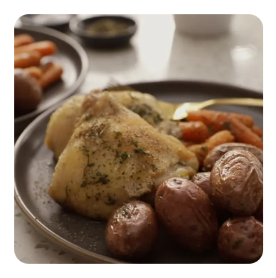 A close-up plate of roasted potatoes, chicken and carrots