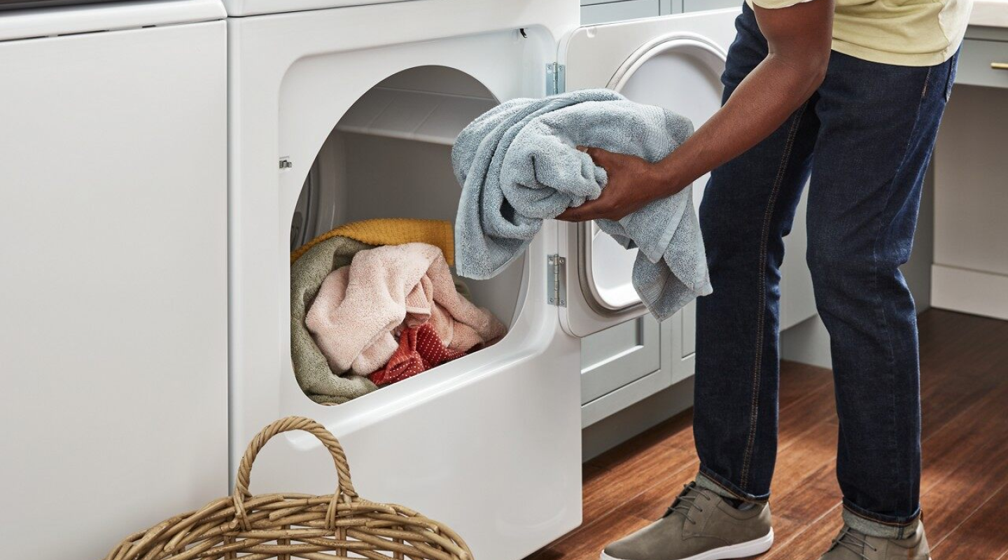 Person placing a load of towels into the dryer Person placing a load of towels into the dryer