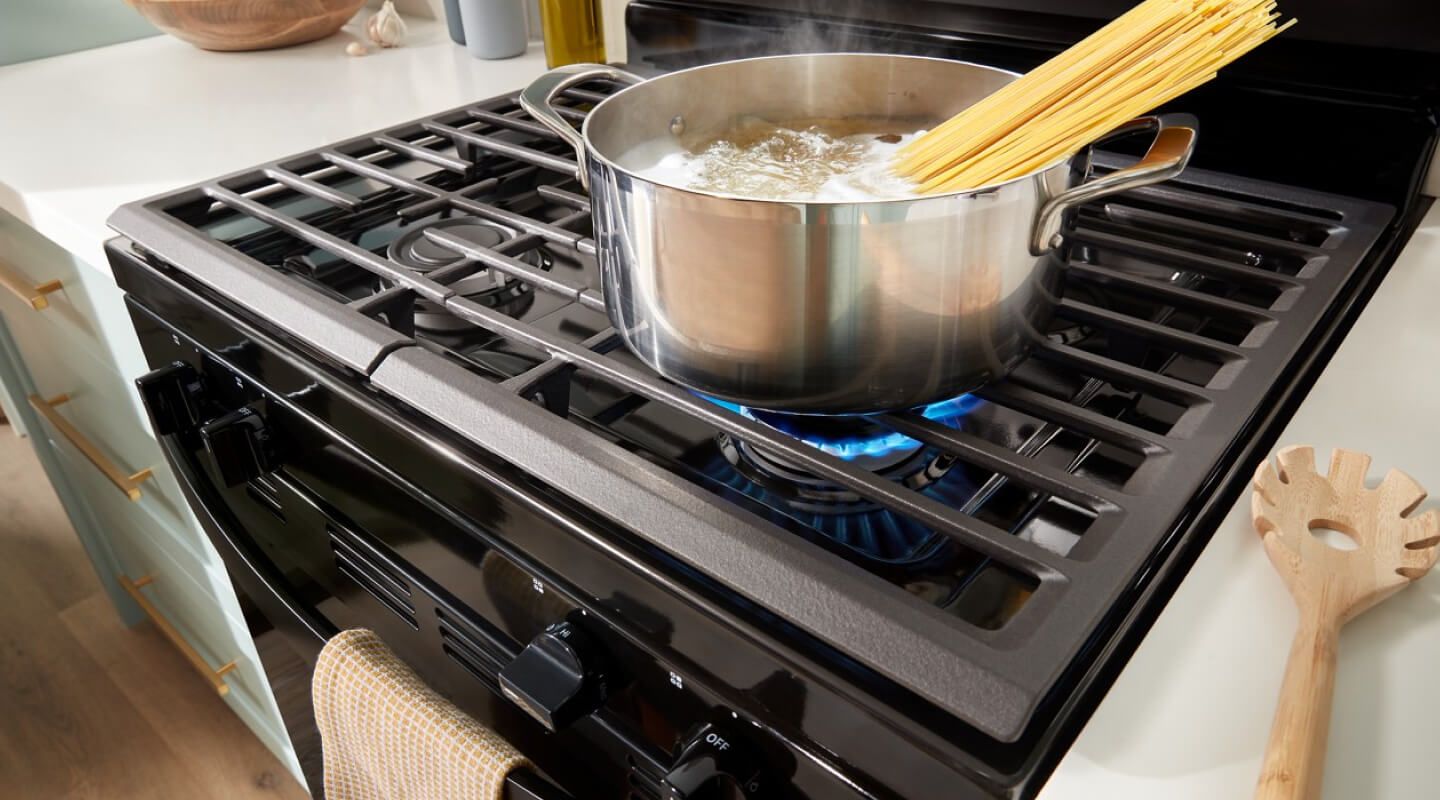 Pasta boiling in a pot on a gas range burner