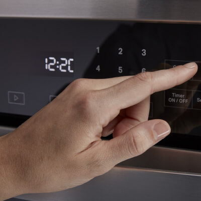 Person selecting a setting on an oven control panel