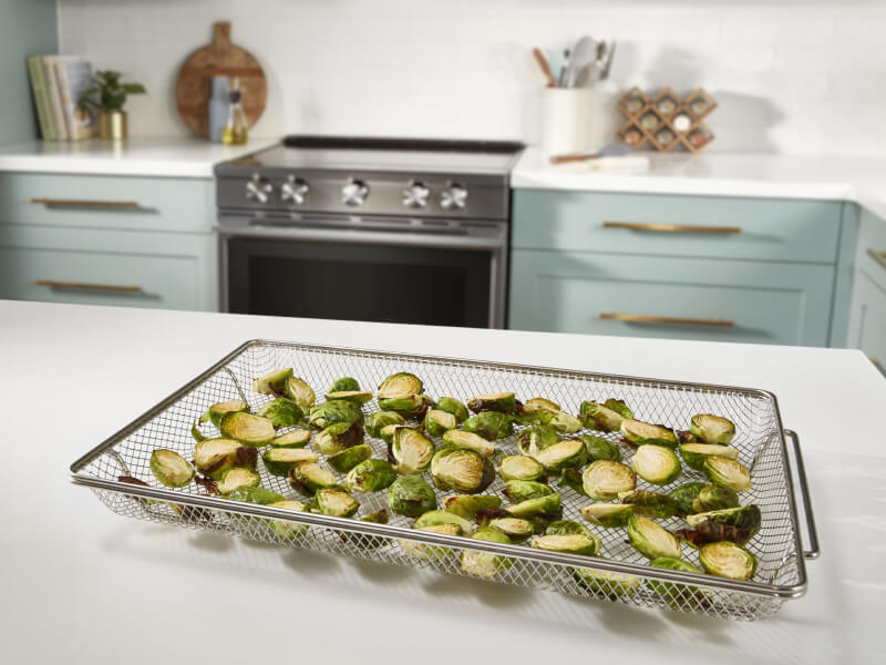 Oven air fried brussel sprouts on air fryer basket on counter