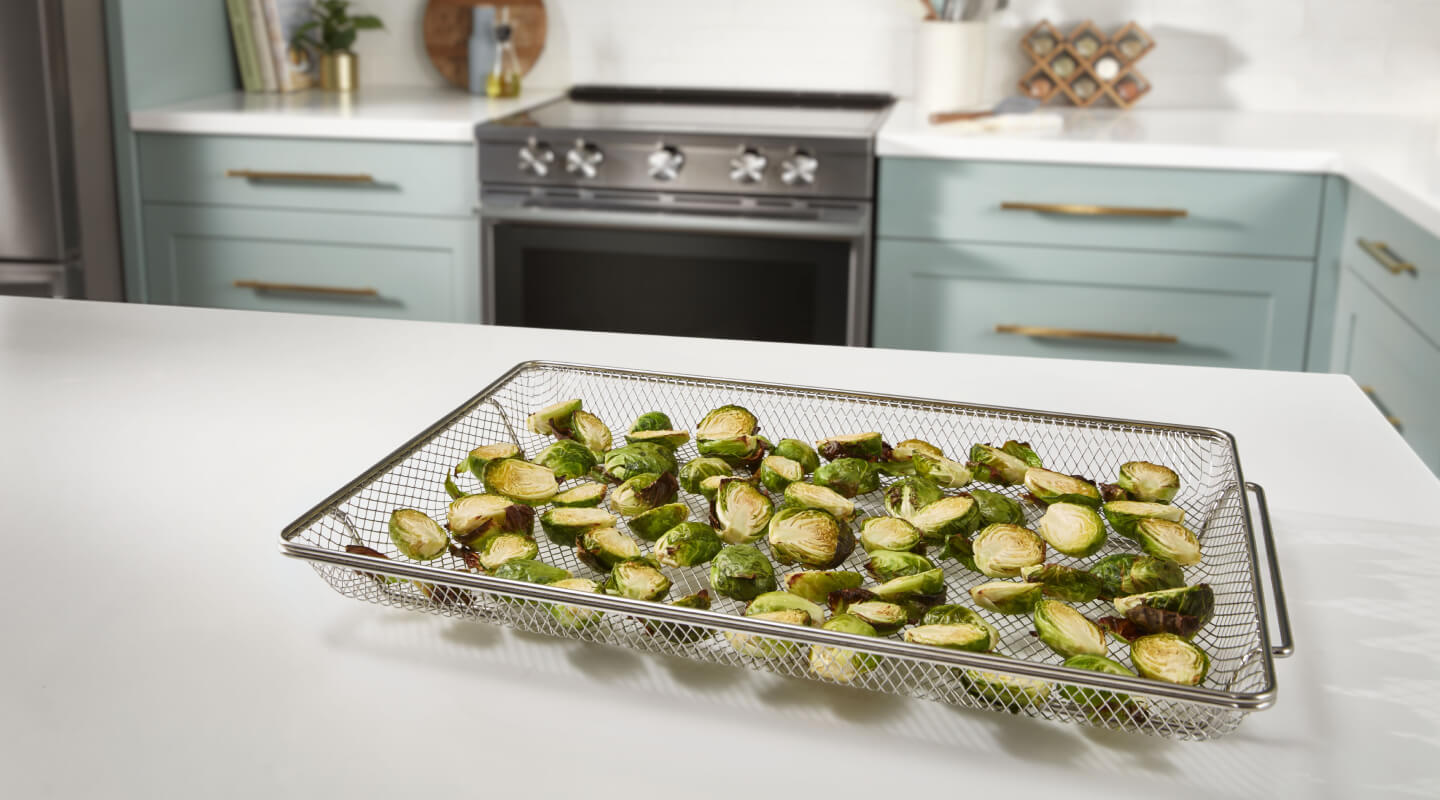 Oven air fried brussel sprouts on air fryer basket on counter Oven air fried brussel sprouts on air fryer basket on counter