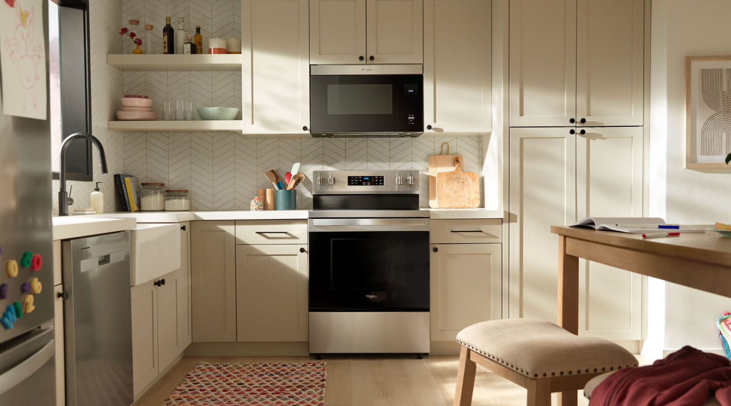 An over-the-range microwave in a modern kitchen with cream cabinets
