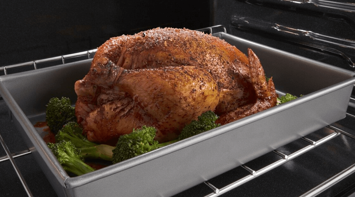 Seasoned cooked turkey in a roasting pan surround by stalks of broccoli Seasoned cooked turkey in a roasting pan surround by stalks of broccoli