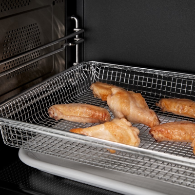 Chicken wings air frying in a basket