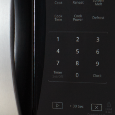 Closeup of a person using touch controls on a microwave