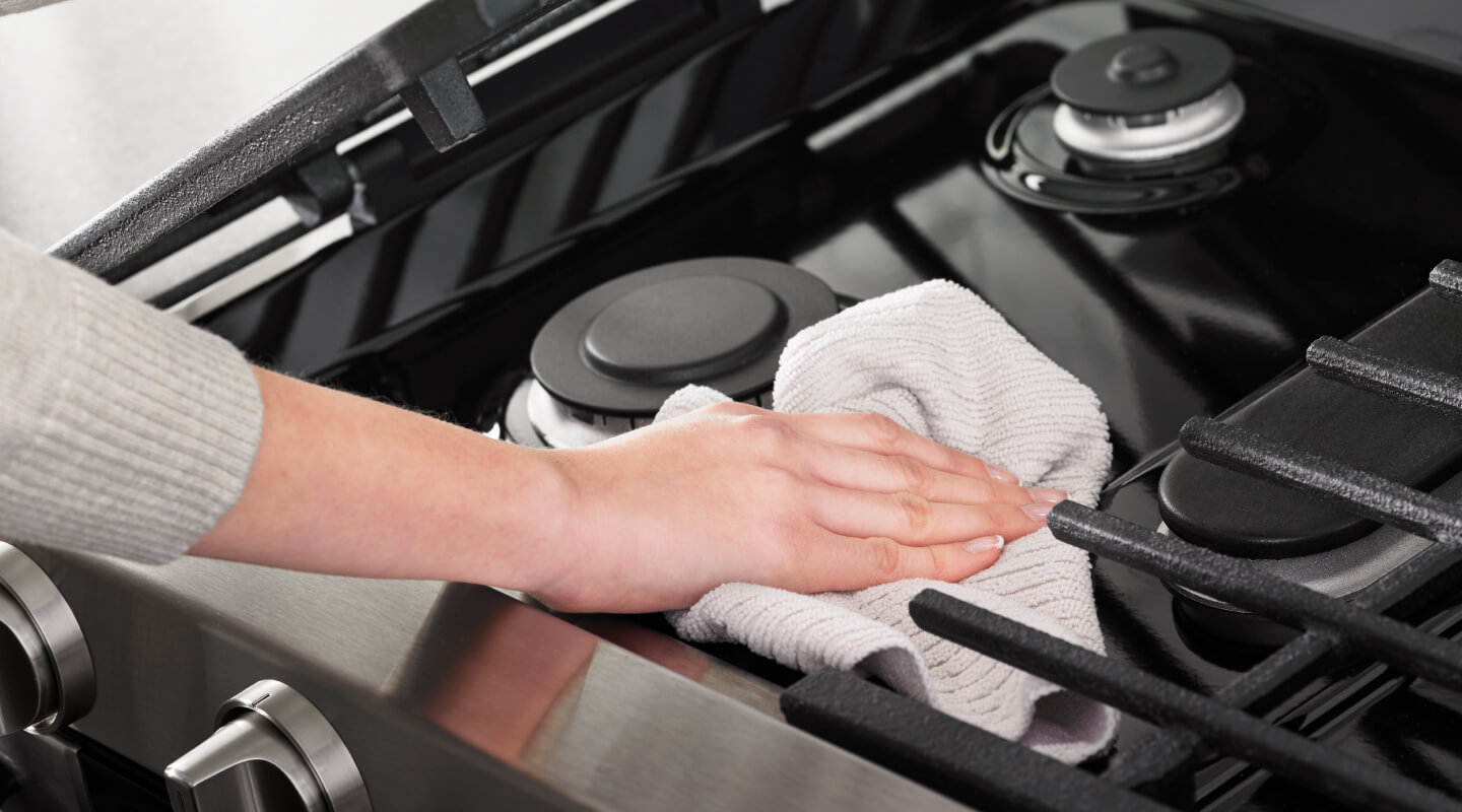 A hand cleaning the exterior of an oven