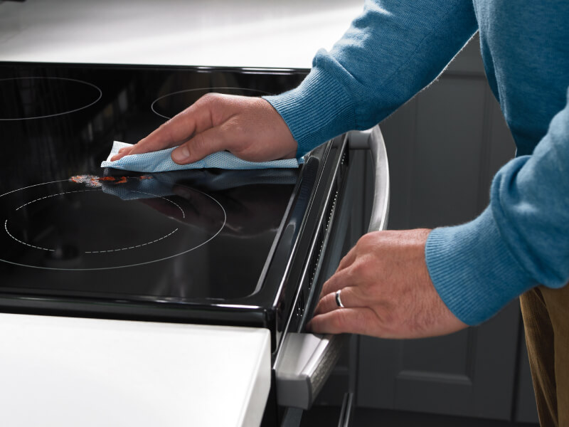 A hand wiping the cooking surface of an electric range