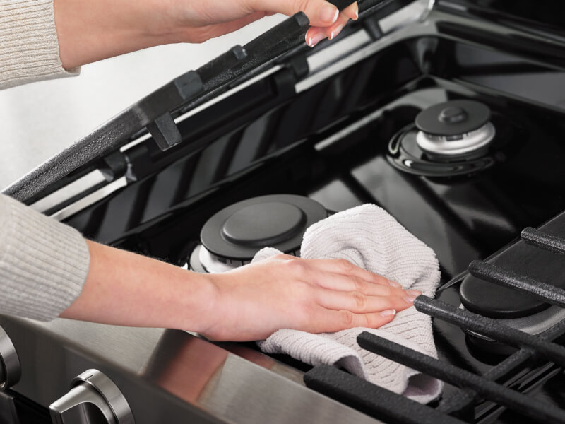 A hand cleaning the exterior of an oven