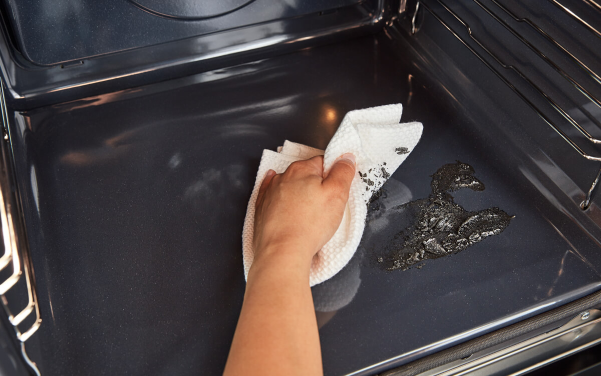 A hand wiping the inside of an oven
