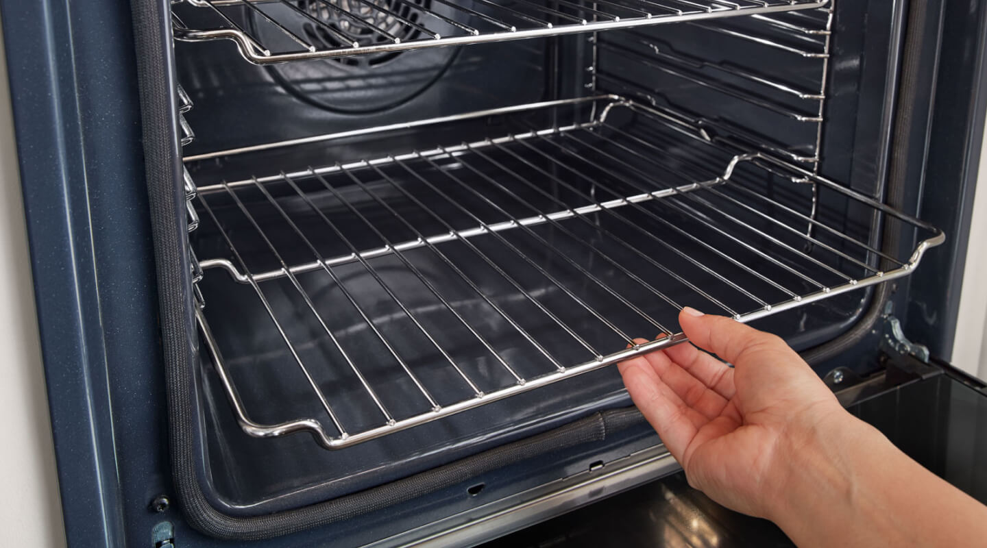 A person placing the bottom rack of an oven A person placing the bottom rack of an oven