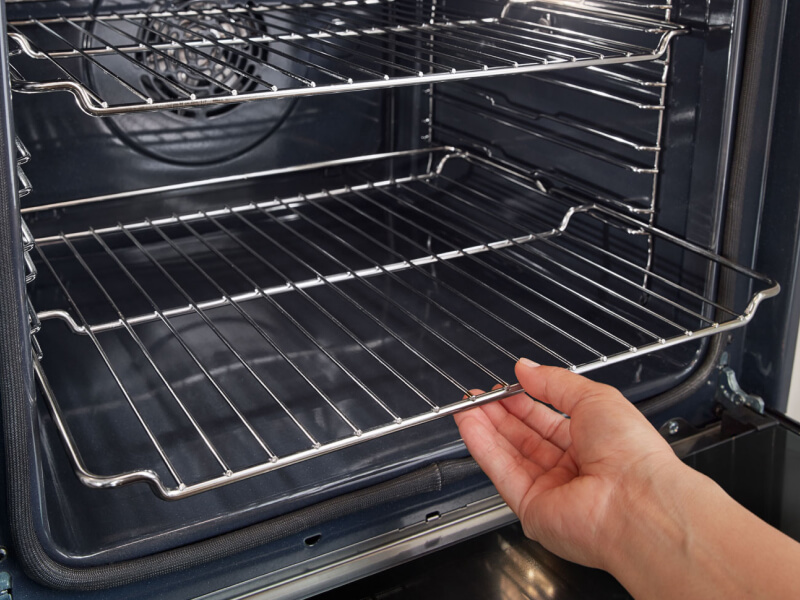 A person placing the bottom rack of an oven A person placing the bottom rack of an oven