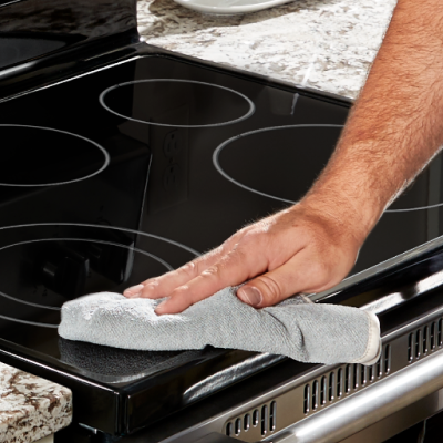 Person wiping down an electric stovetop with a rag