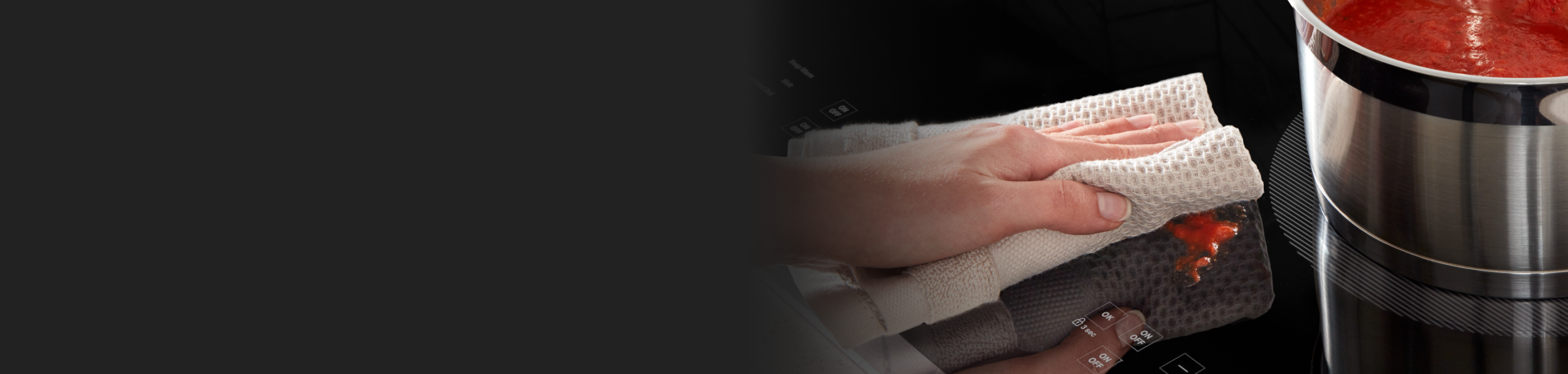 Person cleaning a Whirlpool® induction cooktop with a towel