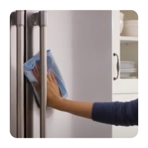 Hand wiping a stainless steel refrigerator with a dry cloth
