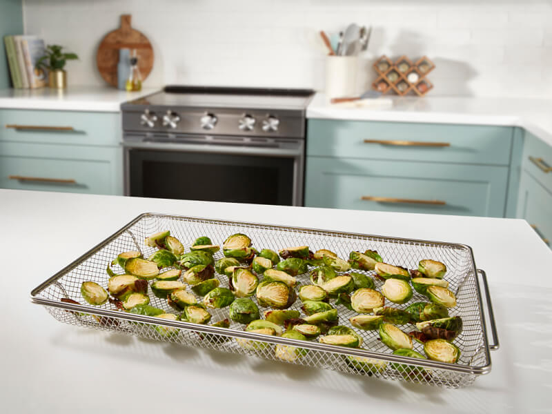 Sliced Brussels sprouts inside an air fryer basket