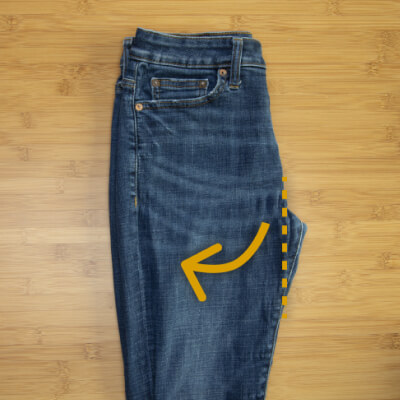 A pair of jeans folded in half with arrows instructing readers to tuck in the crotch portion