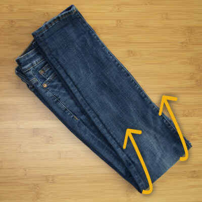 A pair of jeans with arrows instructing readers to fold the pants in half lengthwise