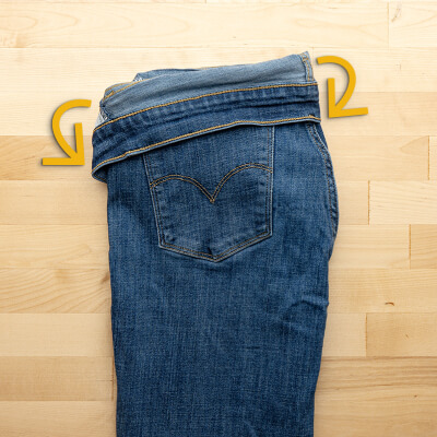 Jeans folded in half, lengthwise, with the waistband folded over