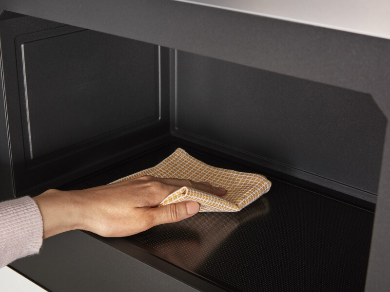 Person wiping the inside of the microwave