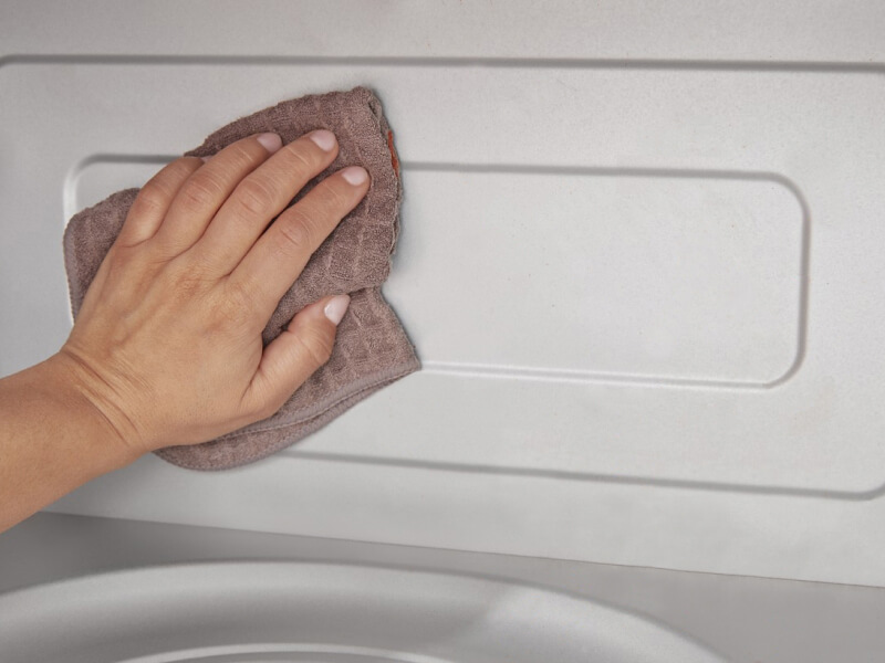 Person wiping the inside of a microwave with a cloth