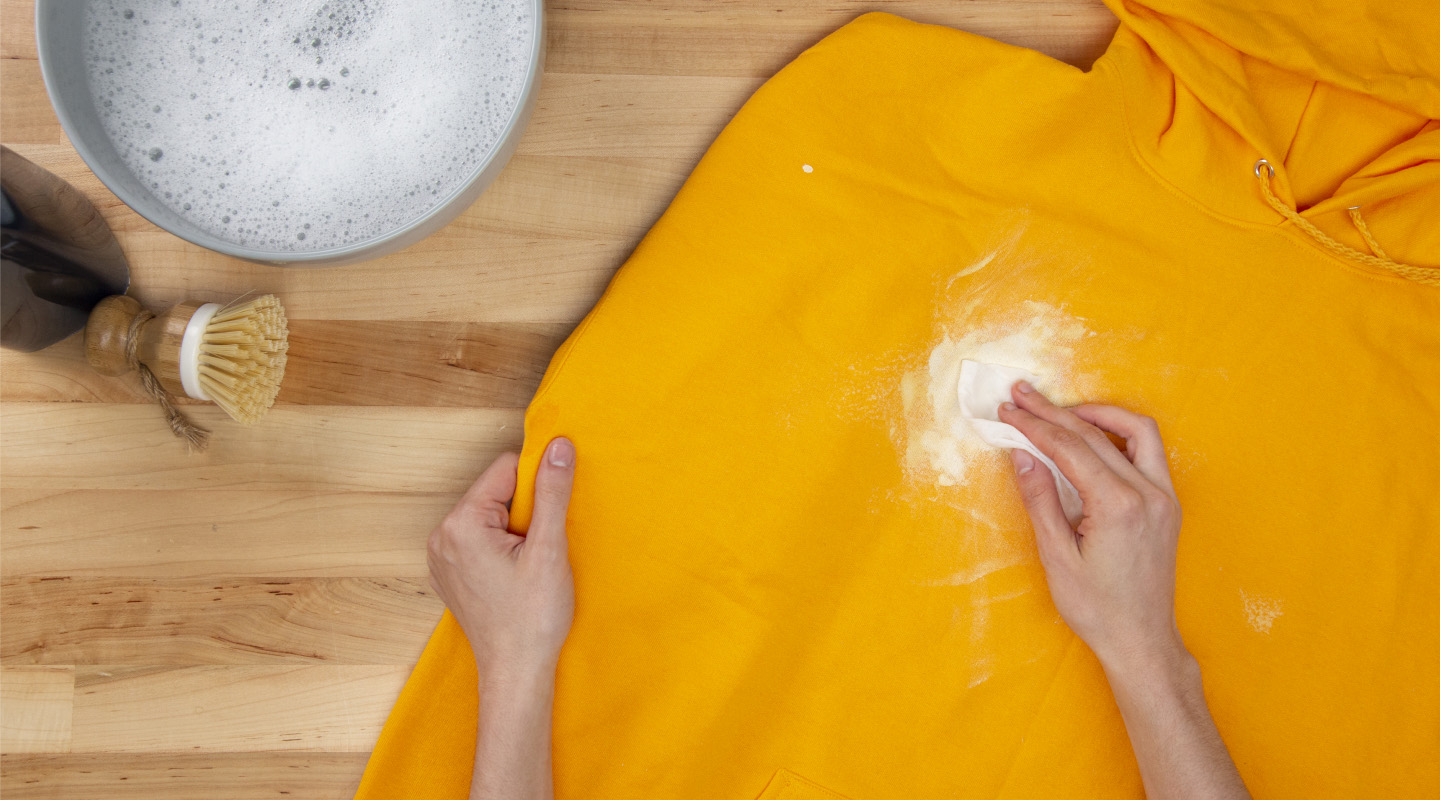 Hand blotting white paint on a yellow sweatshirt with a paper towel Hand blotting white paint on a yellow sweatshirt with a paper towel