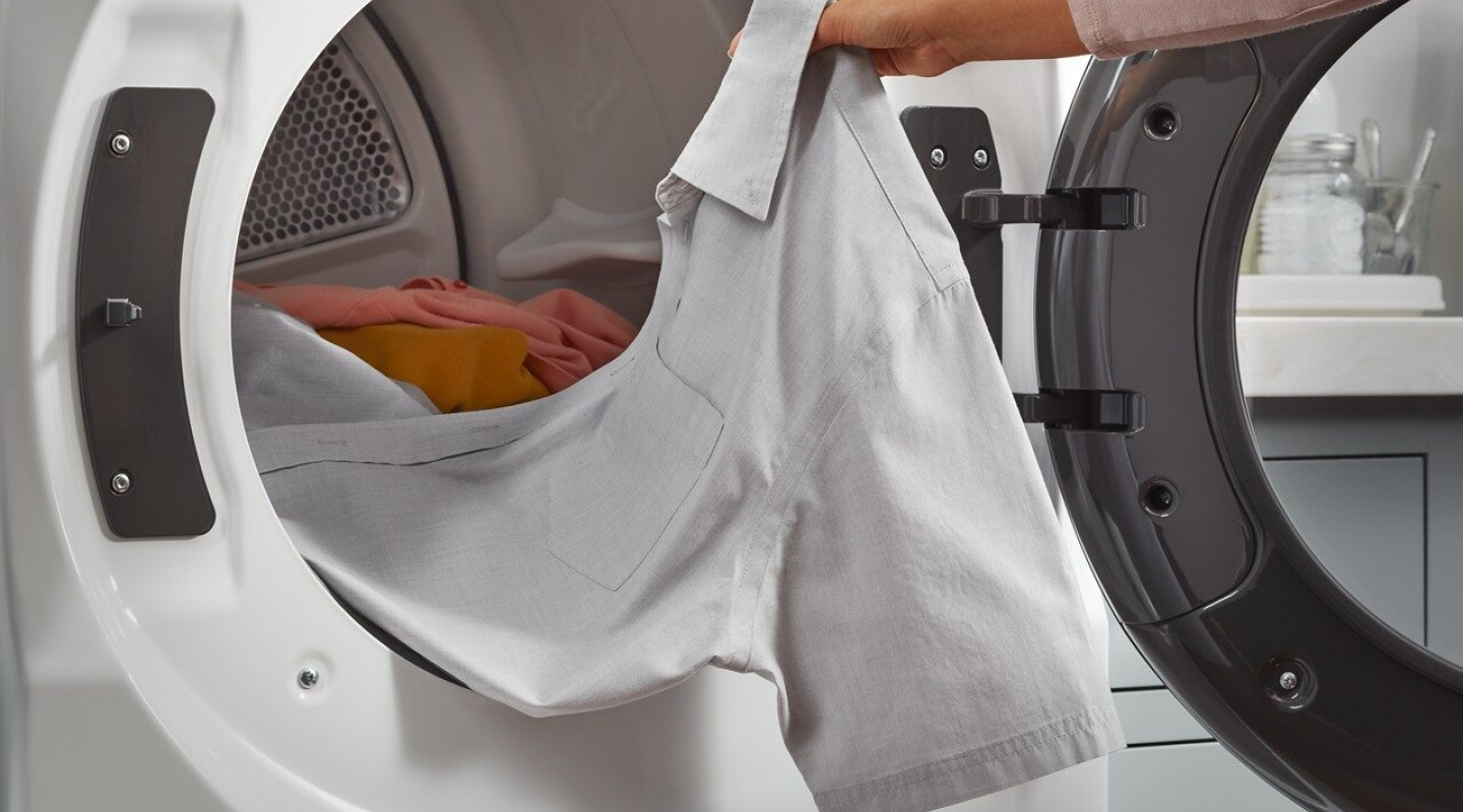 Person removing a shirt from a dryer Person removing a shirt from a dryer