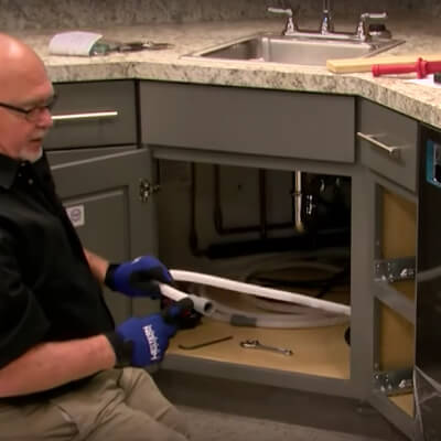 A person connecting dishwasher hoses