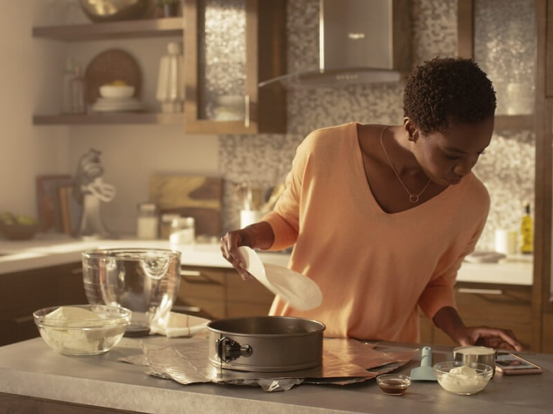 Woman in kitchen reading recipe on her phone 