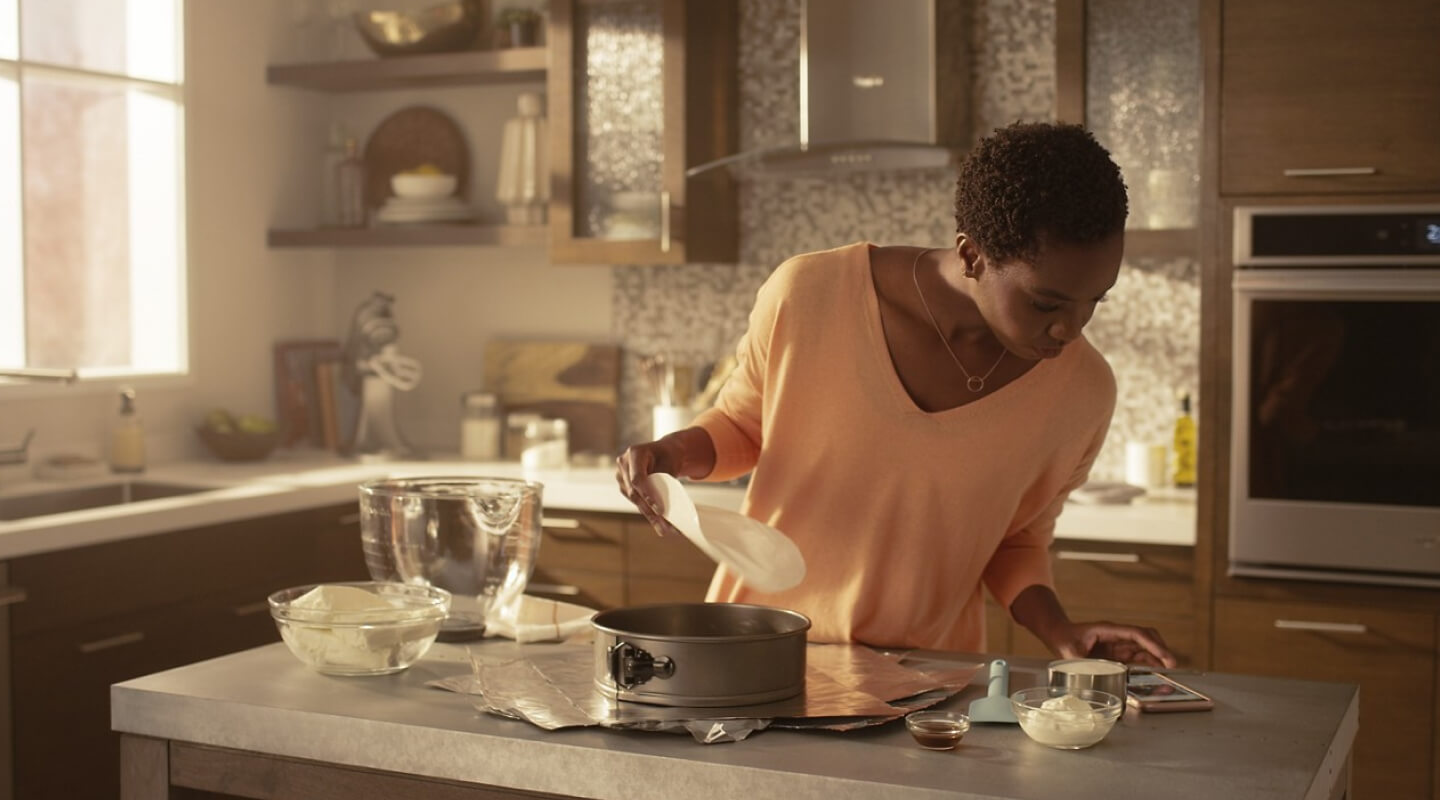 Woman in kitchen reading recipe on her phone 