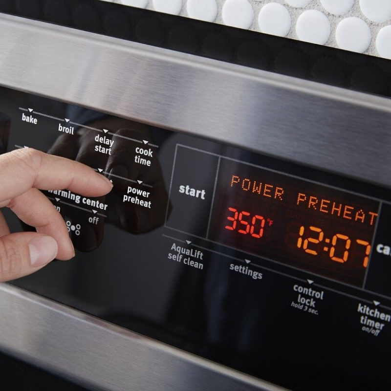 Hand making a preheat selection on the oven