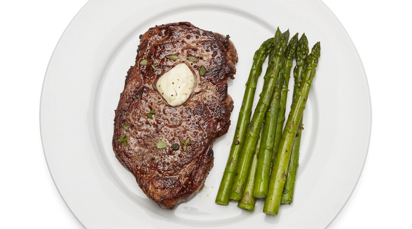 Plate of steak with melted butter and asparagus