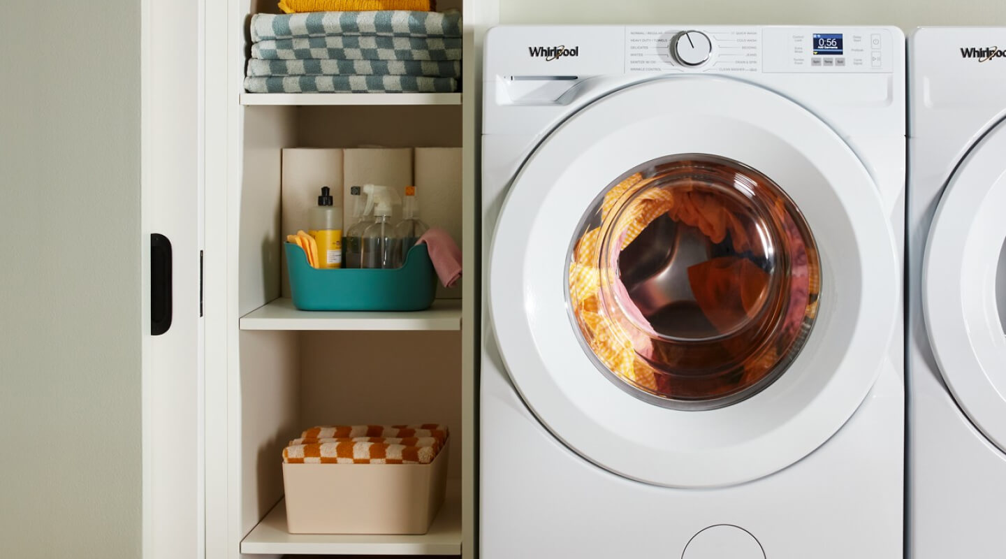 A laundry area with a white, front load washer full of laundry