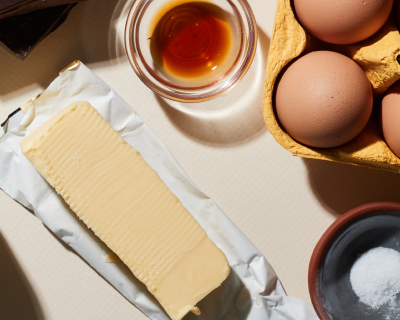 Open stick of butter next to cooking oil, eggs and seasoning