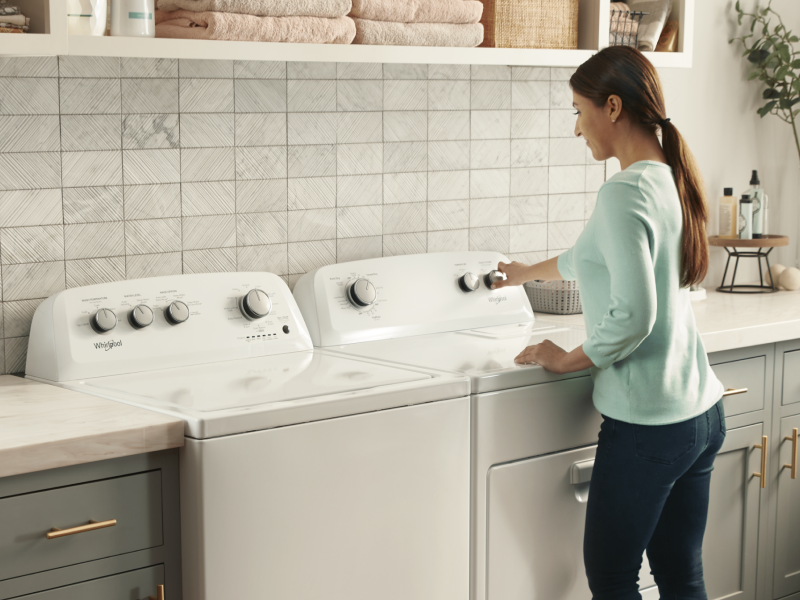A woman using a Whirlpool® dryer next to a matching washer A woman using a Whirlpool® dryer next to a matching washer