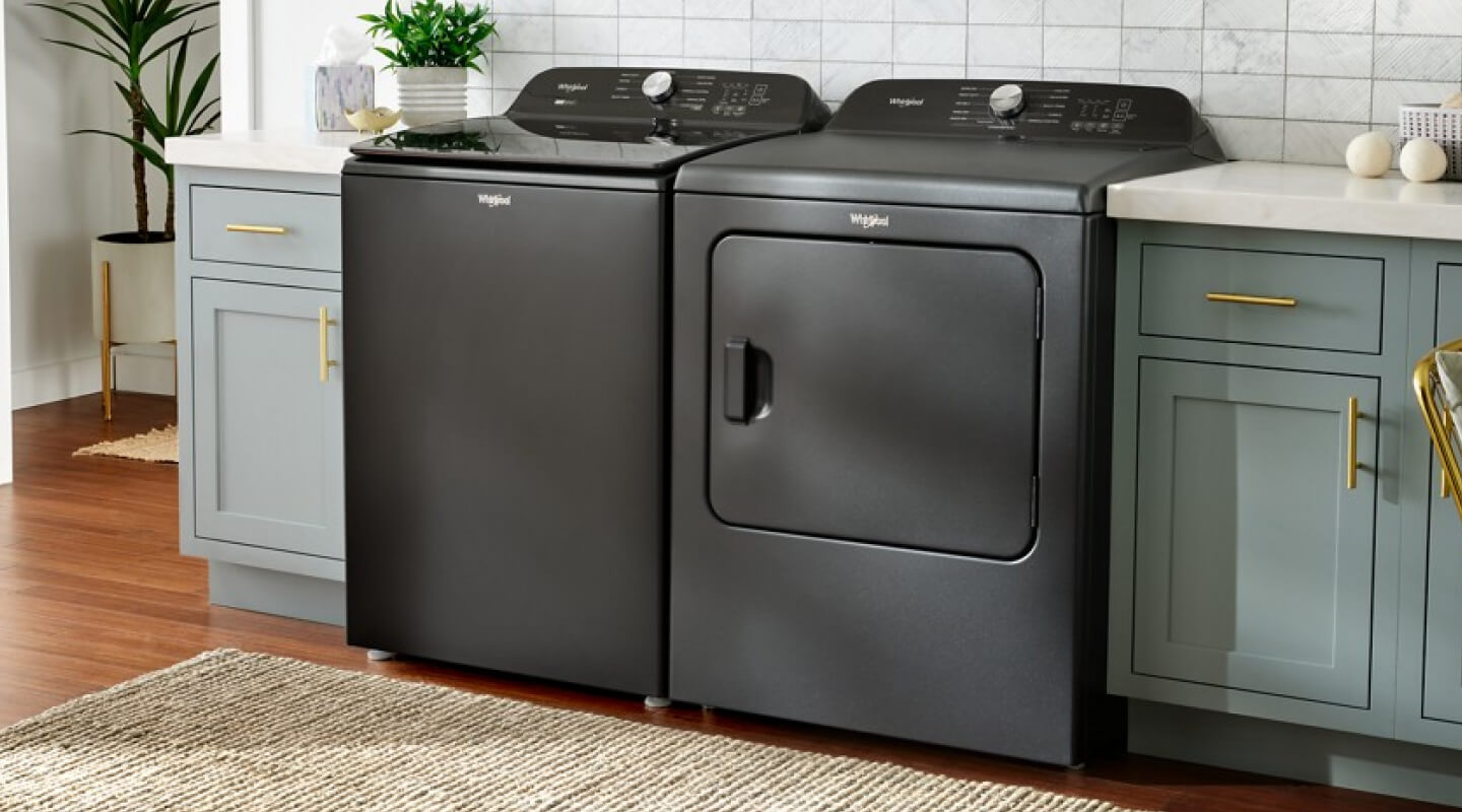 A black Whirlpool® Top Load Washer and Dryer set in a laundry room