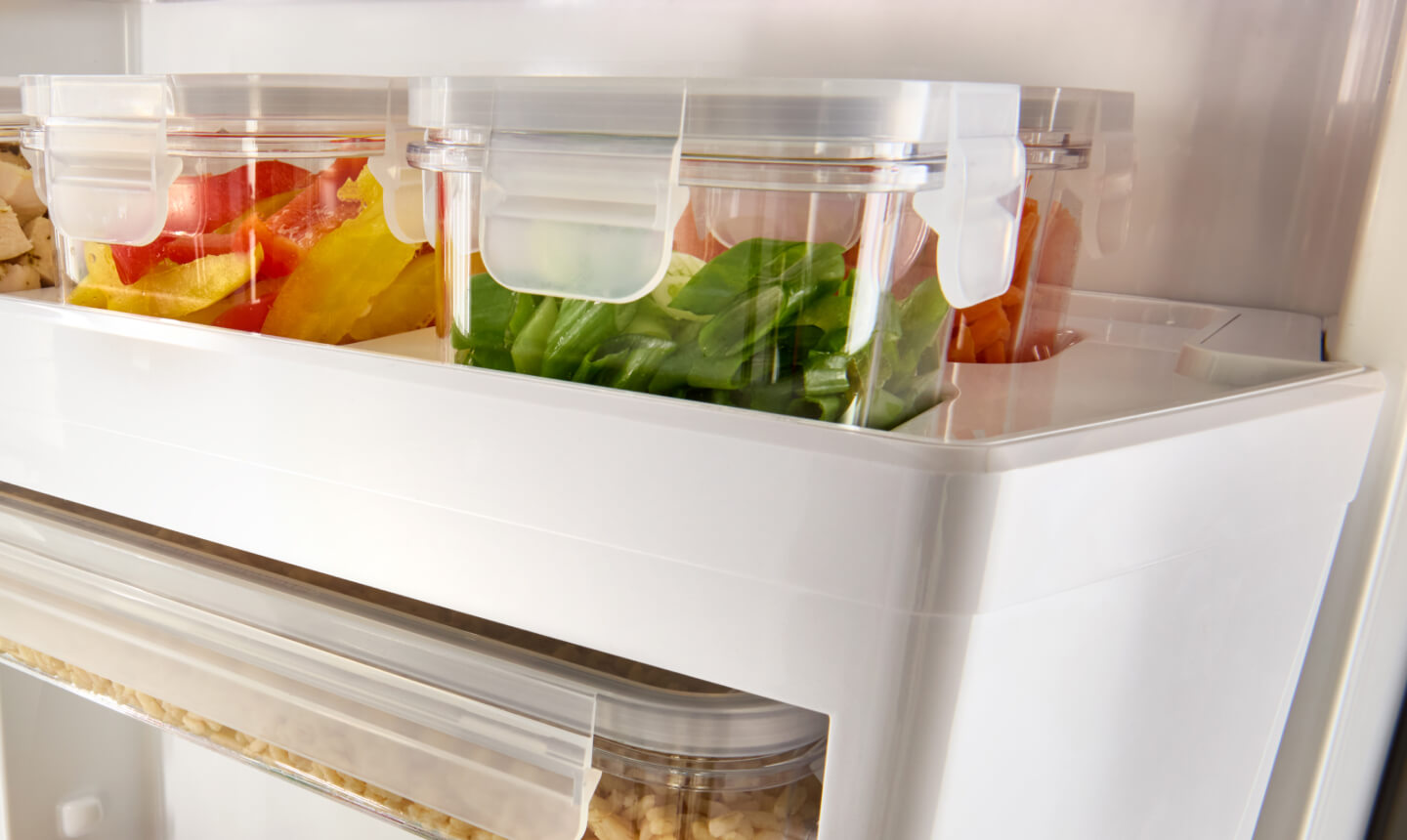 Fresh herbs and vegetables in plastic containers in a refrigerator