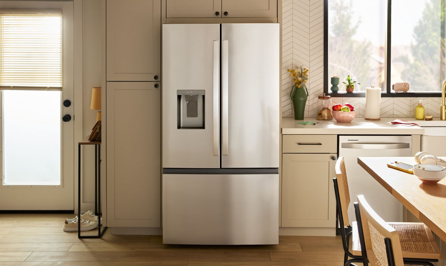 An all-white kitchen with a stainless steel French door refrigerator