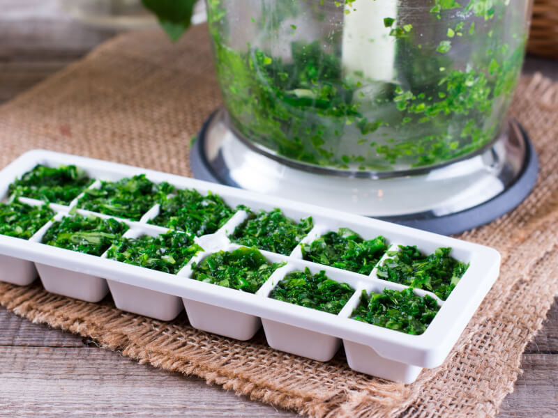 Chopped herbs in a white ice tray 