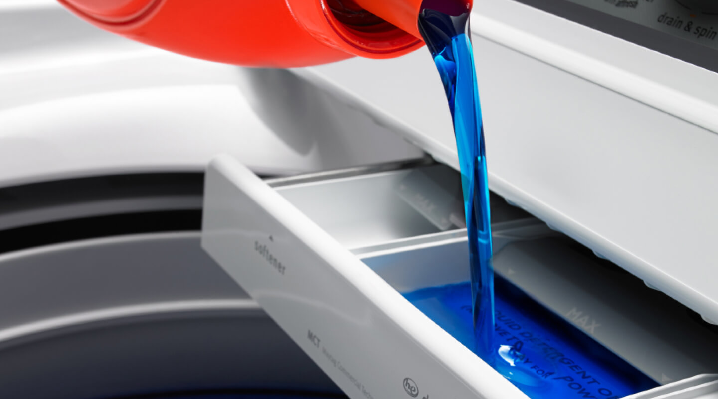 Liquid laundry detergent pouring into washer