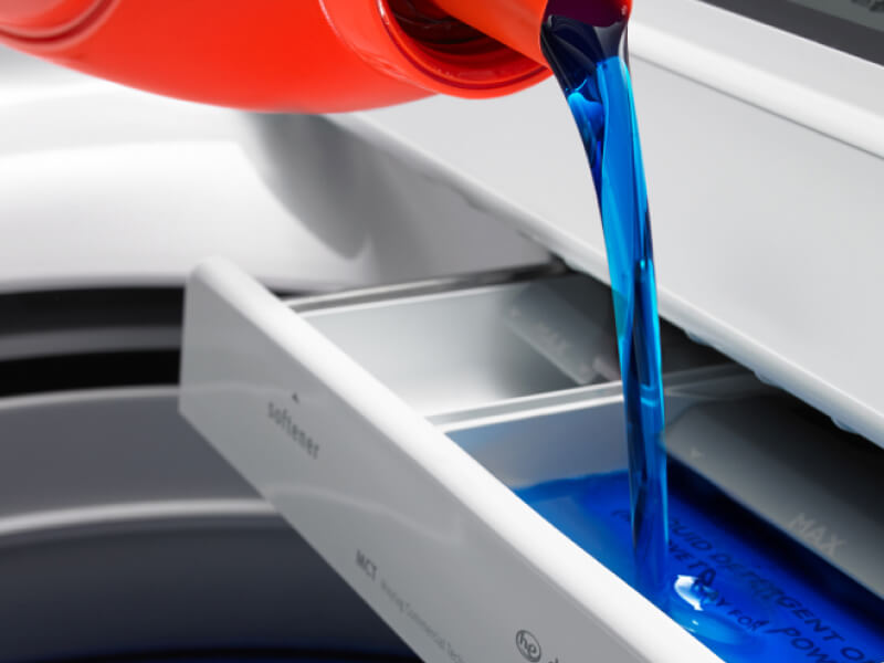 Liquid laundry detergent pouring into washer