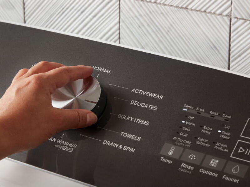 Hand turning the knob on a Whirlpool® Top Load Washer