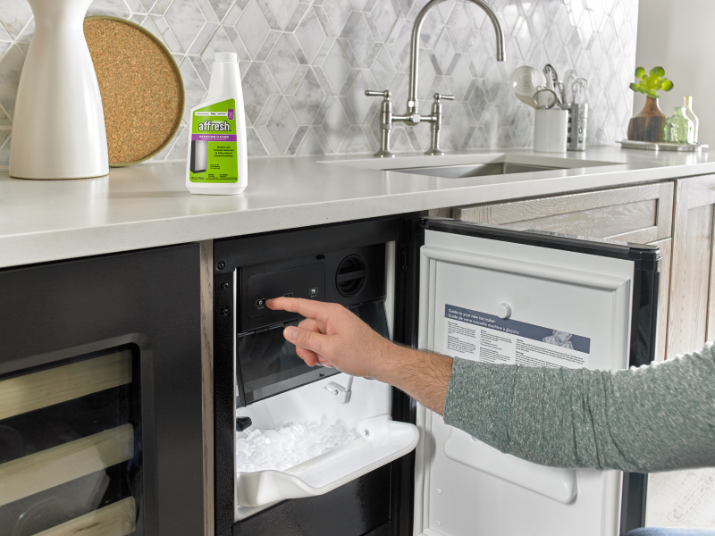 Person opening a built-in icemaker next to affresh® cleaner Person opening a built-in icemaker next to affresh® cleaner