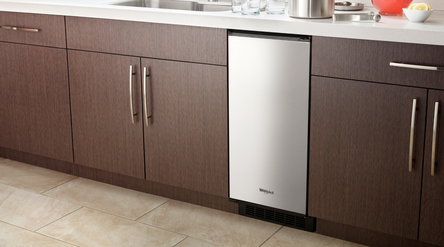 Stainless steel Whirlpool® built-in icemaker set in wood cabinetry